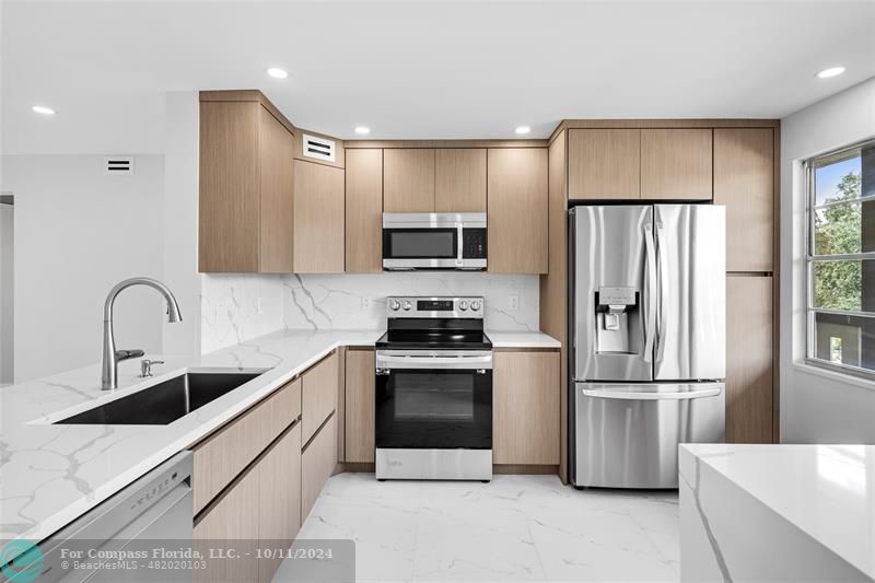 a kitchen with stainless steel appliances granite countertop a refrigerator sink and stove