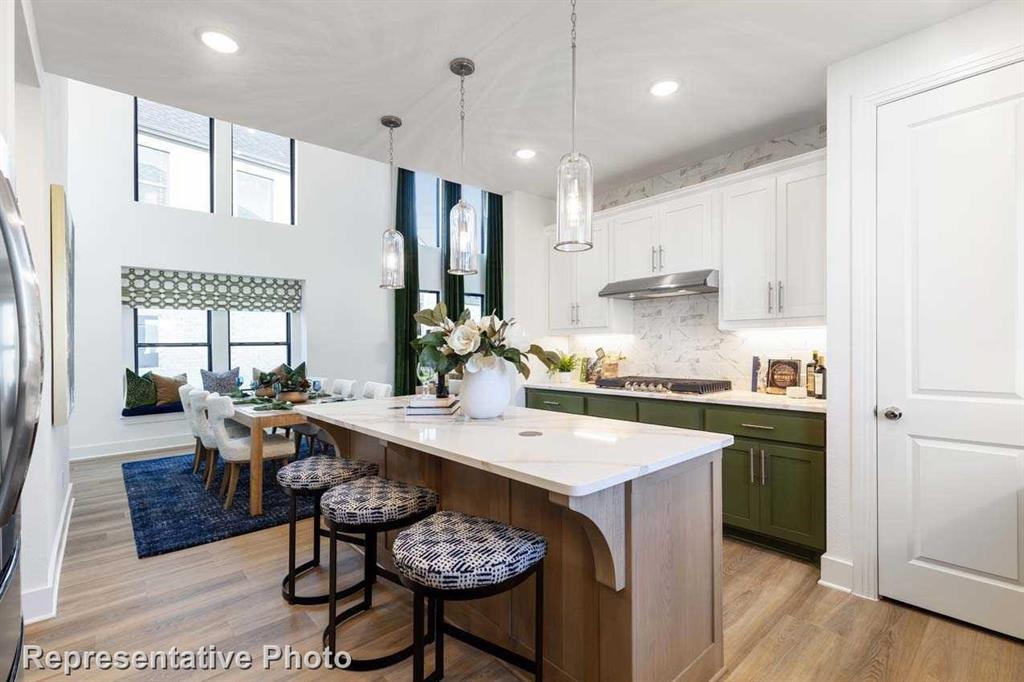 a kitchen with stainless steel appliances kitchen island a table chairs sink and cabinets