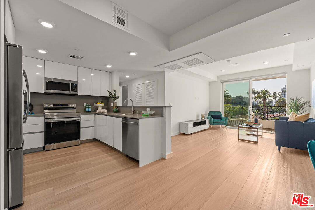 a kitchen with stainless steel appliances kitchen island granite countertop a stove top oven a sink a dining table and chairs with wooden floor