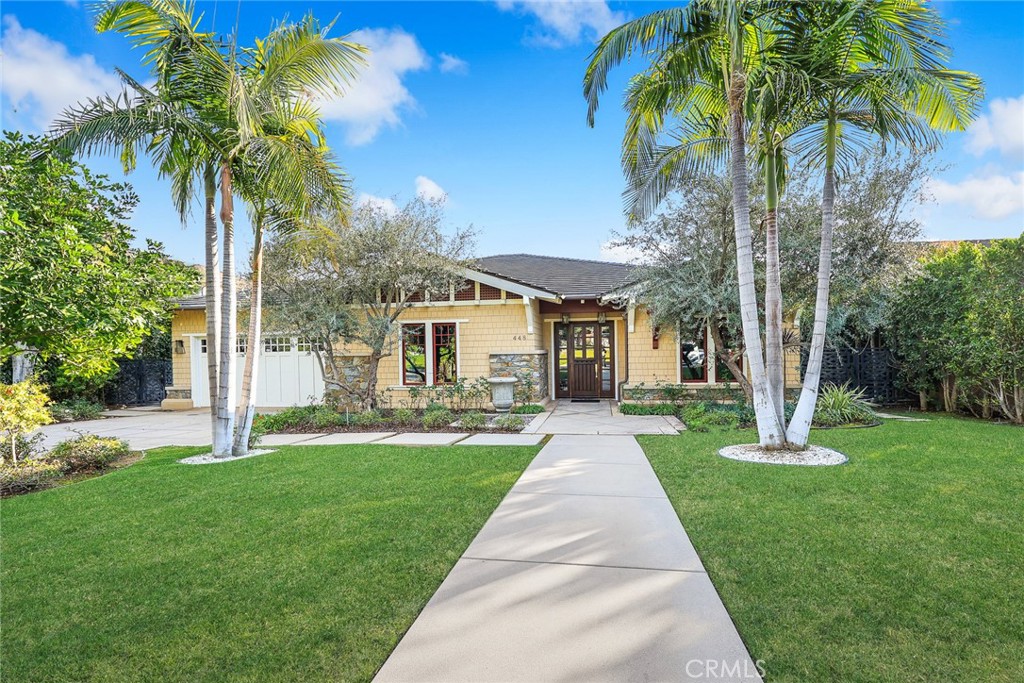 a front view of a house with a yard and palm trees