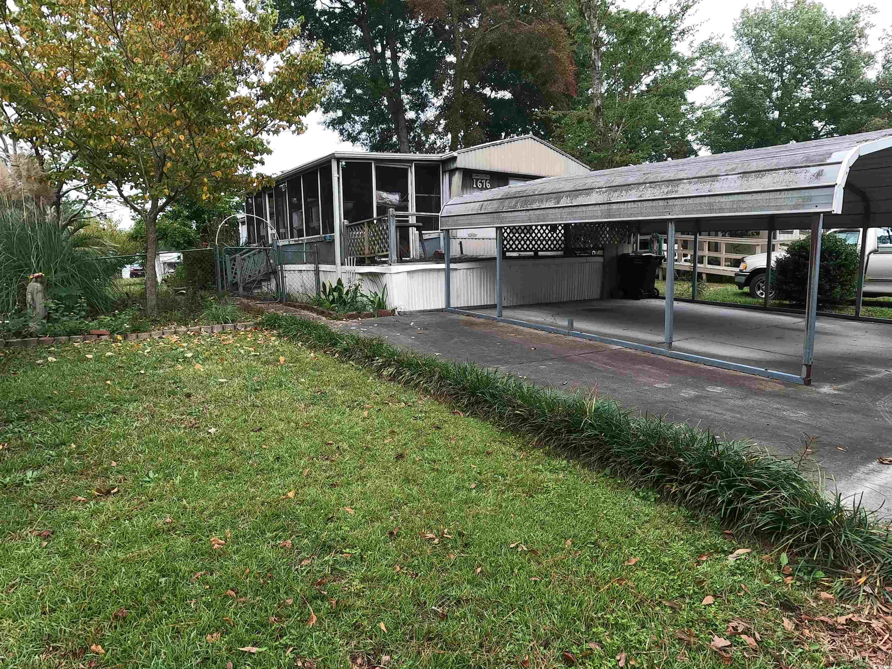 View of property exterior with a lawn, a carport,