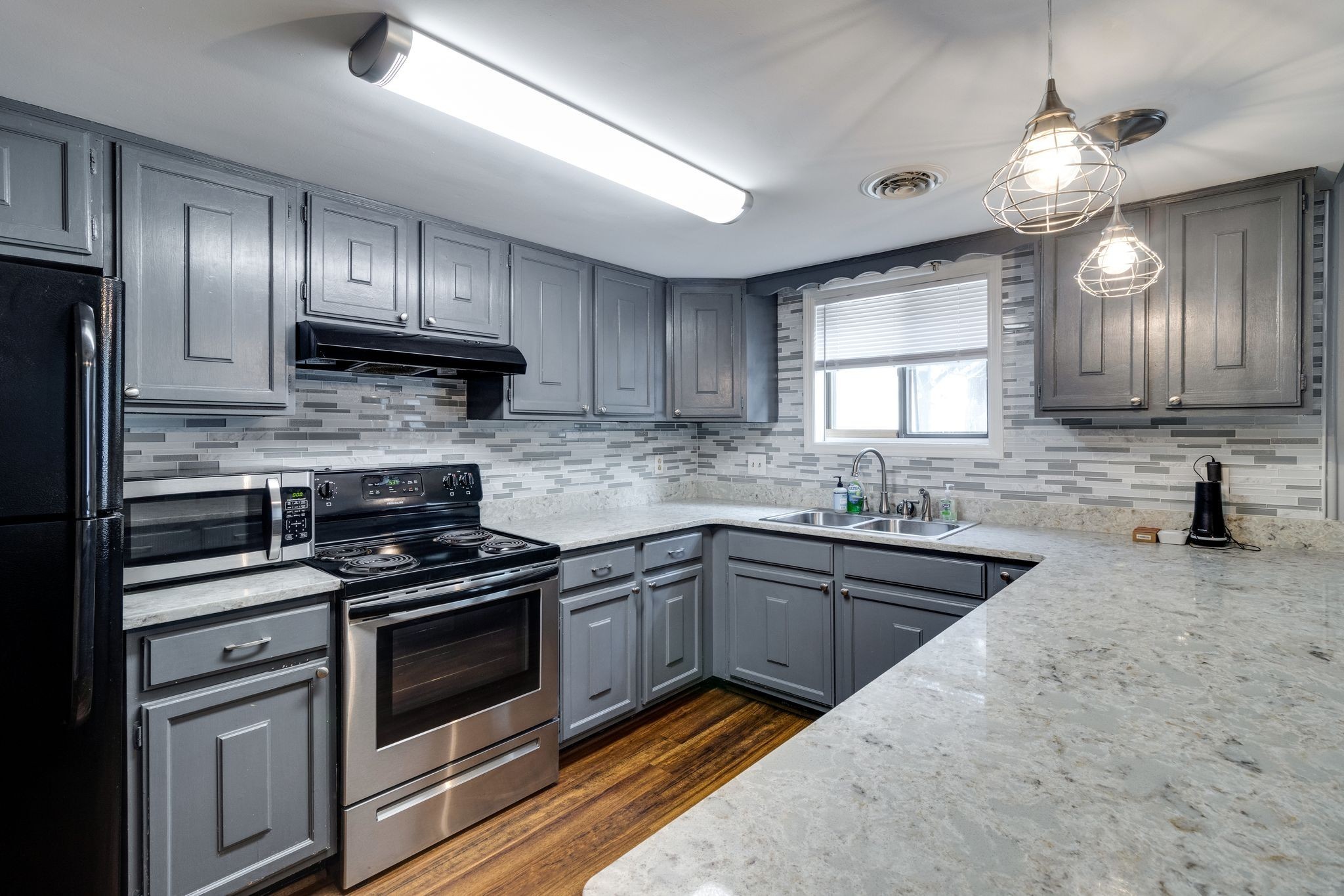 a kitchen with granite countertop stainless steel appliances a stove sink and cabinets