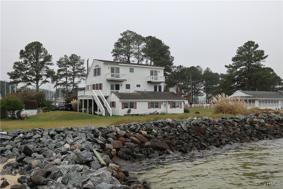 Back of house with a balcony, a yard, and a deck w