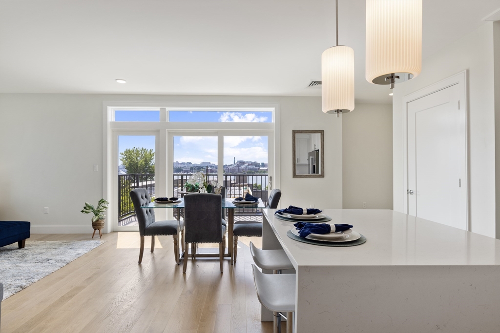 a dining room with wooden floor a chandelier fan a wooden table and chairs