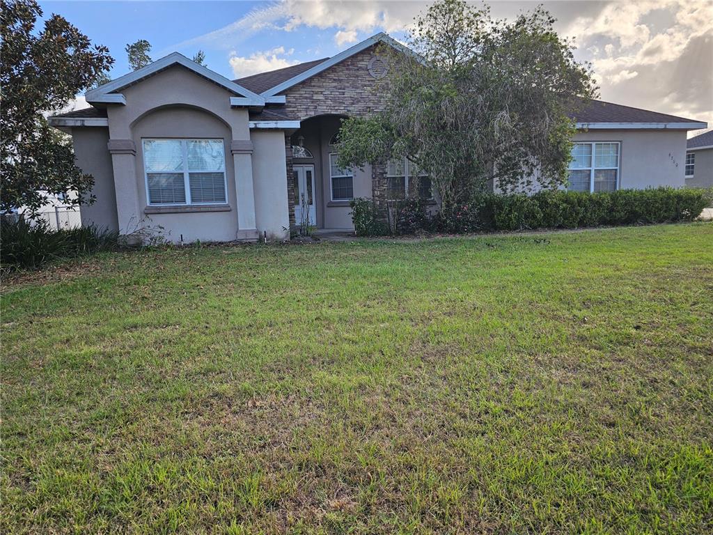 a view of a house with a yard and large tree