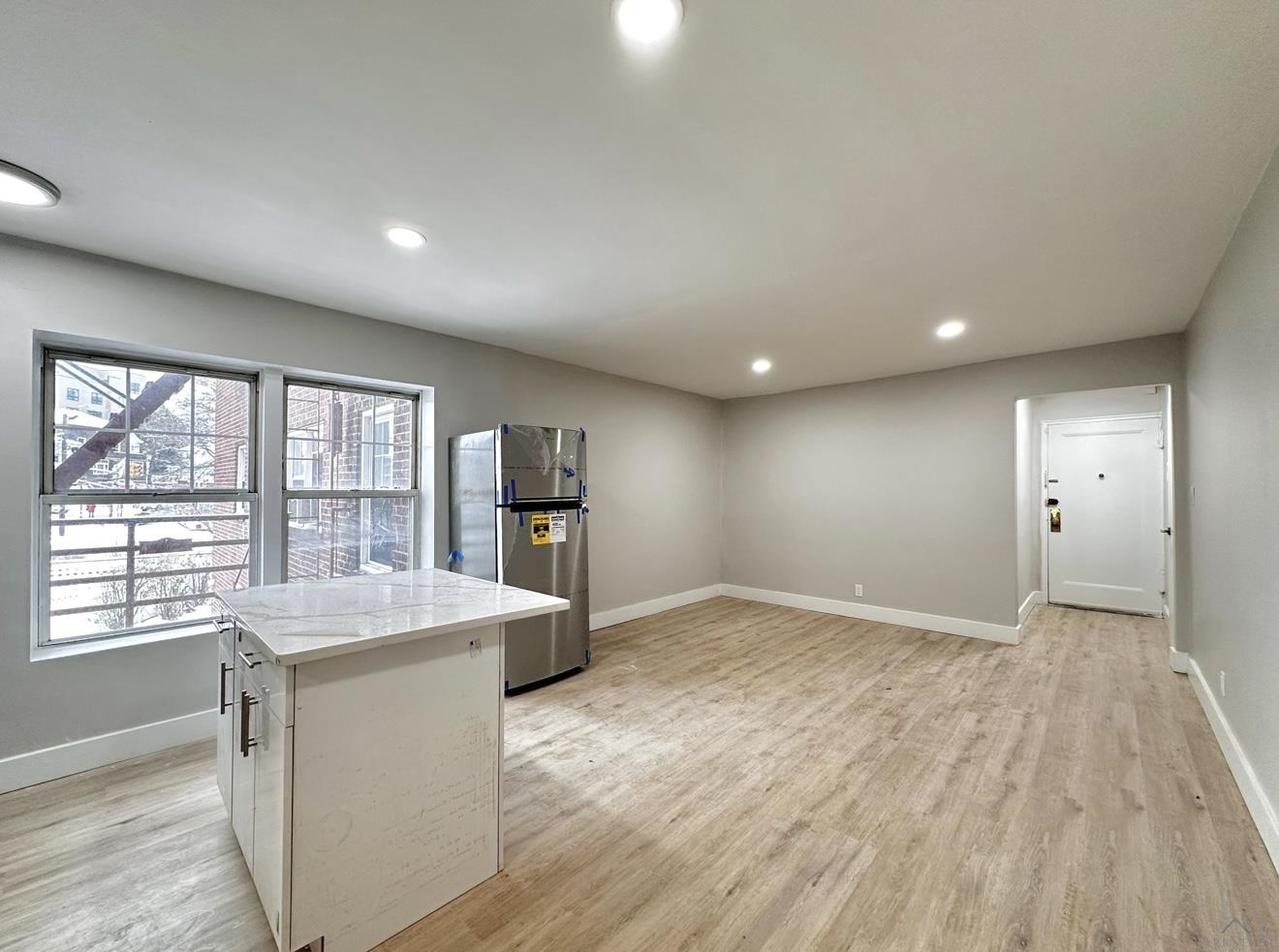 a view of an empty room with a window and wooden floor