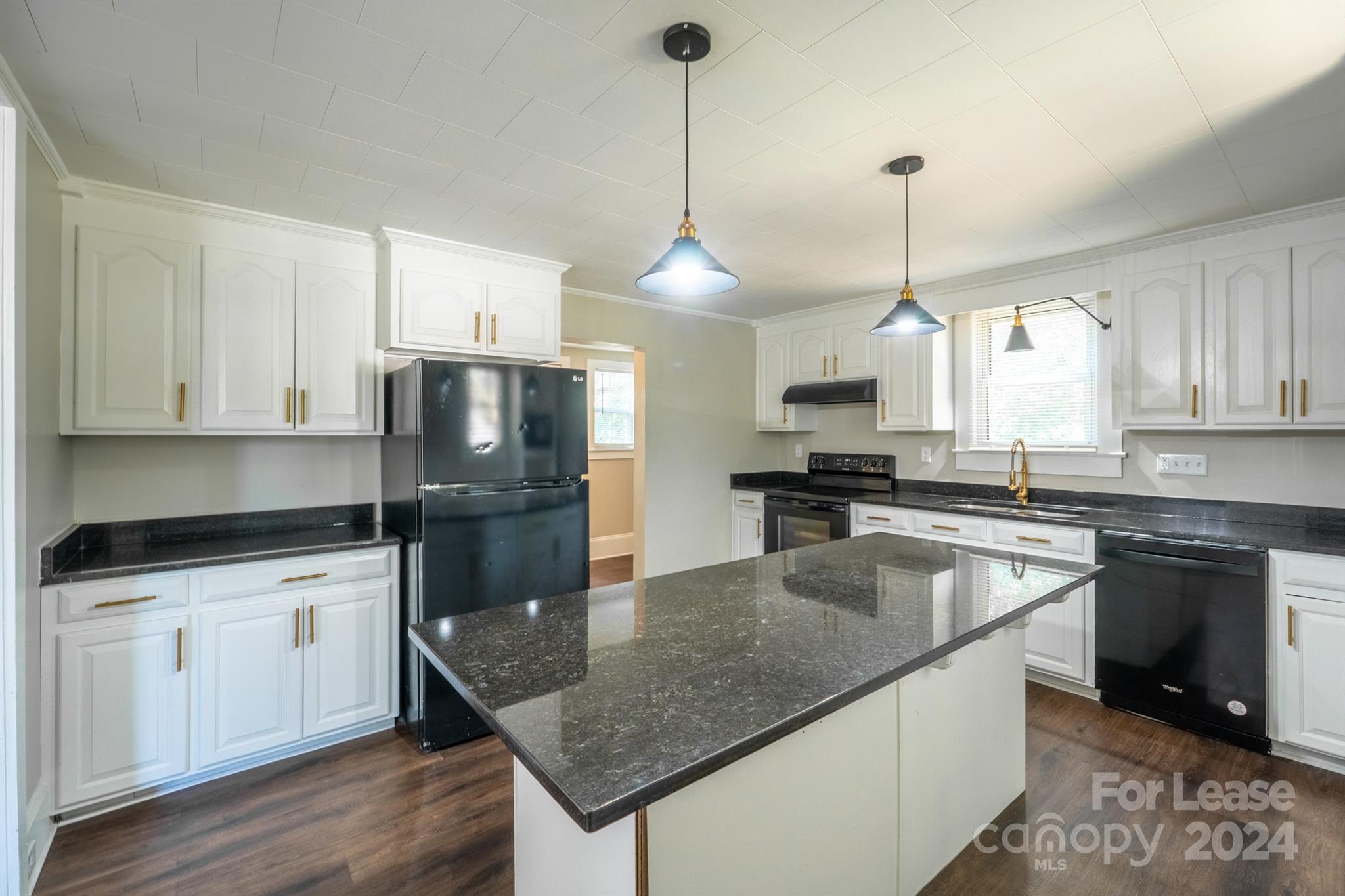 a kitchen with granite countertop a sink a counter space appliances and cabinets