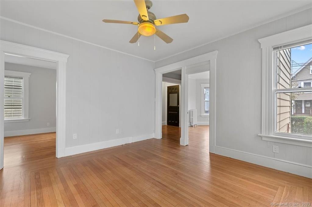 a view of an empty room with window and wooden floor