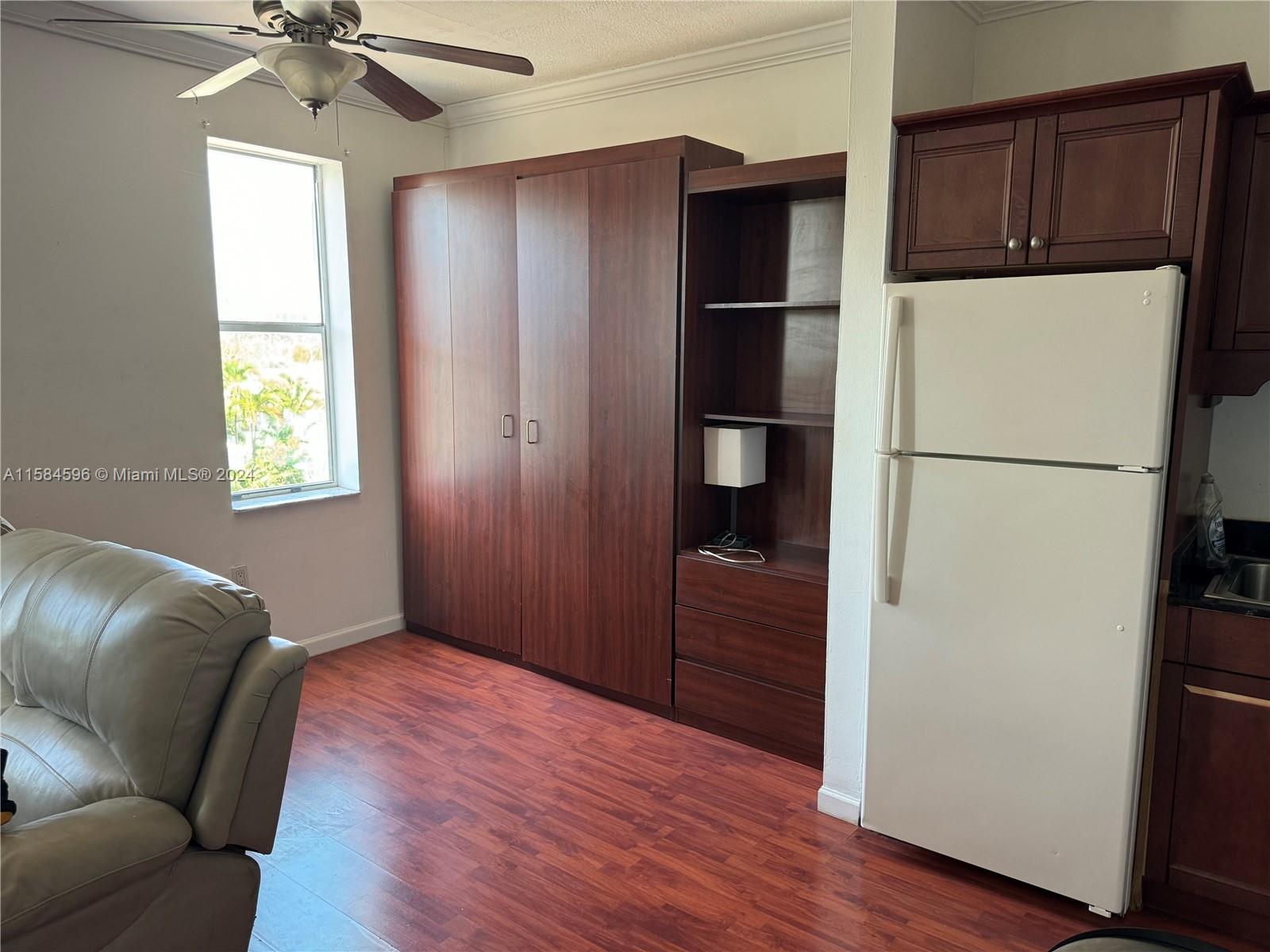 a living room with a refrigerator and a ceiling fan