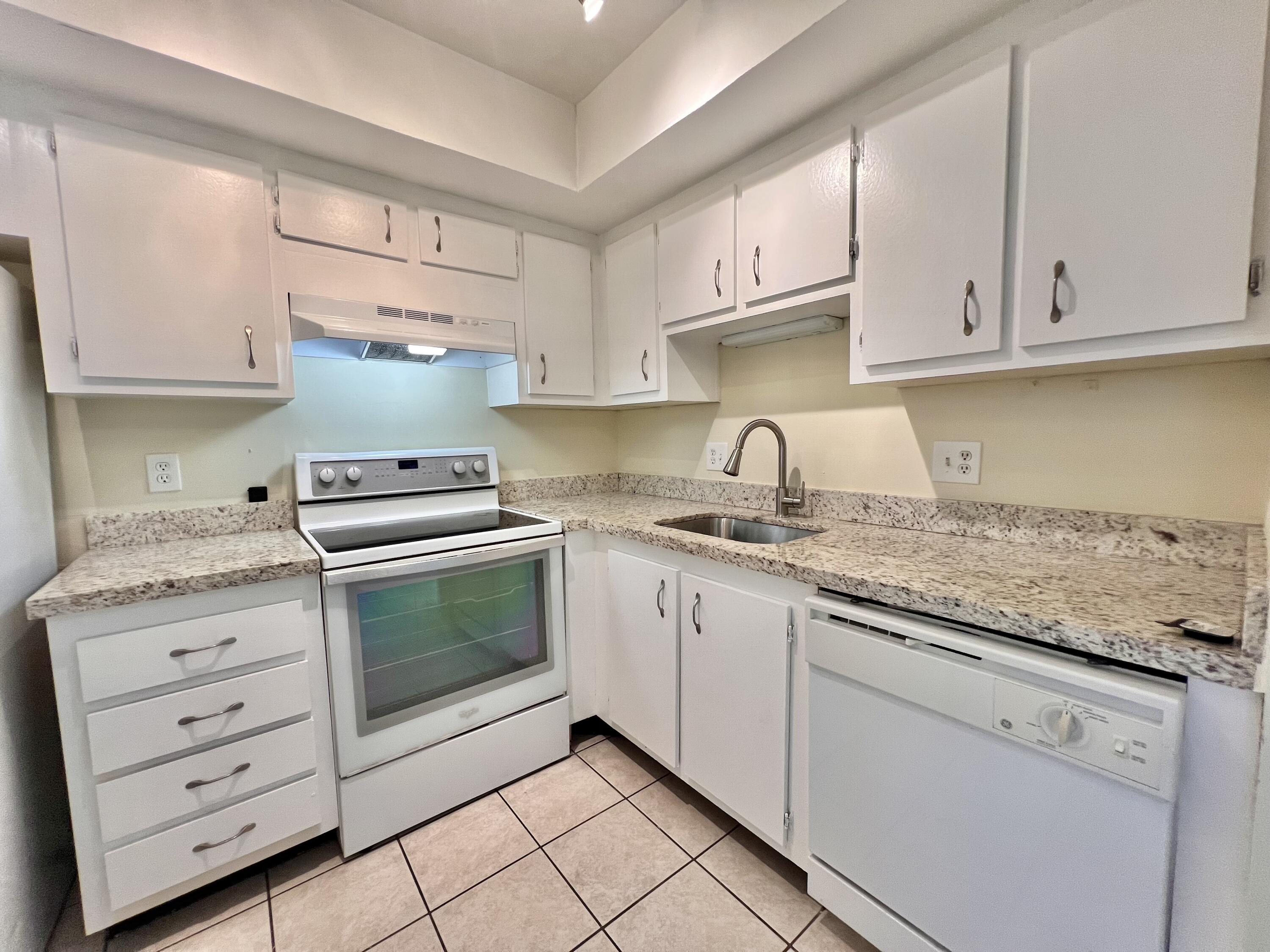 a kitchen with granite countertop white cabinets and white appliances