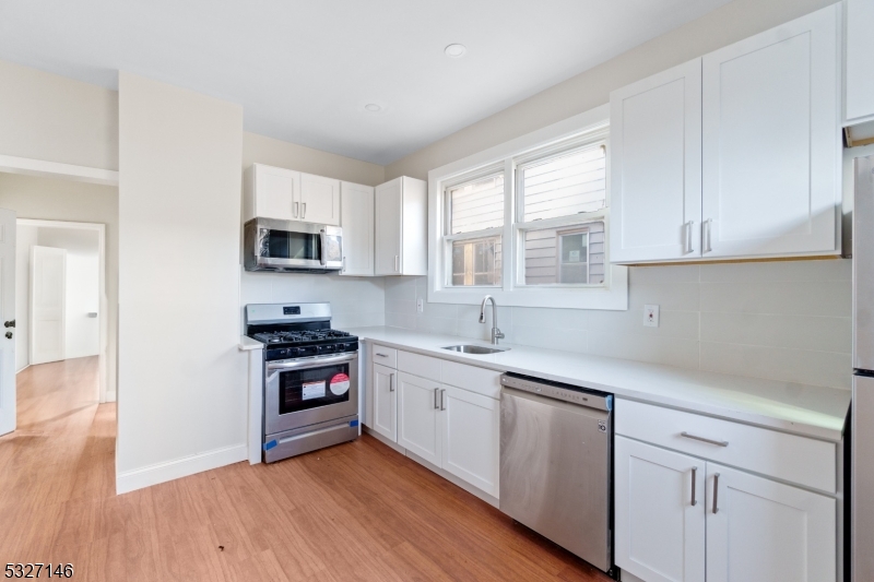 a kitchen with cabinets appliances a sink and a window