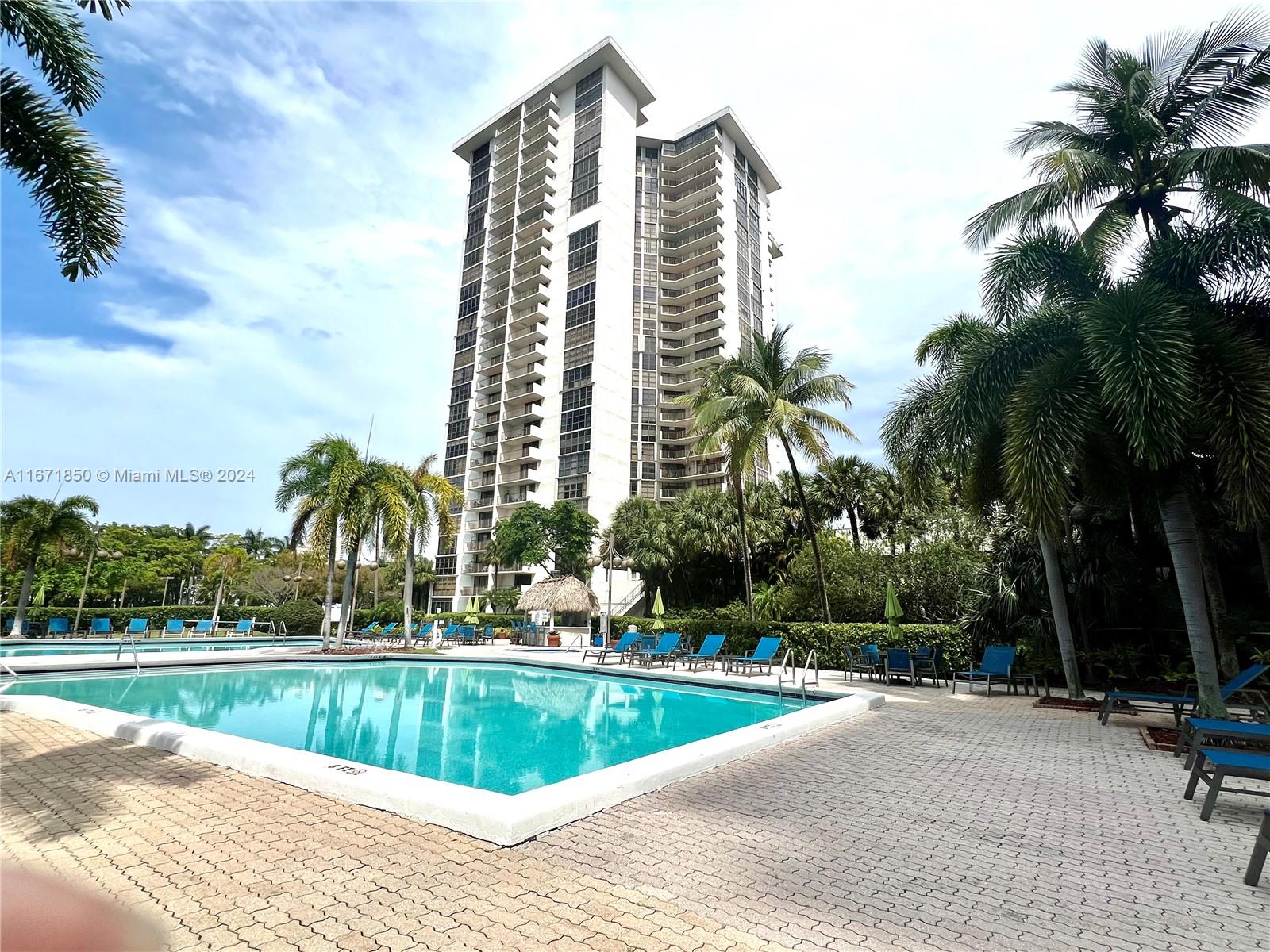 a view of a swimming pool with a lawn chairs and palm trees