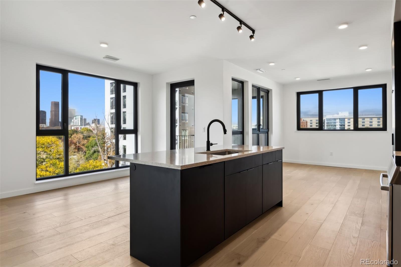 a large hall with stainless steel appliances granite countertop a sink and wooden floor