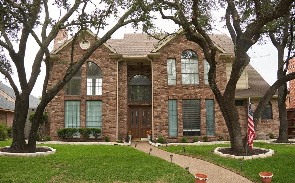 a front view of a house with a yard and large tree