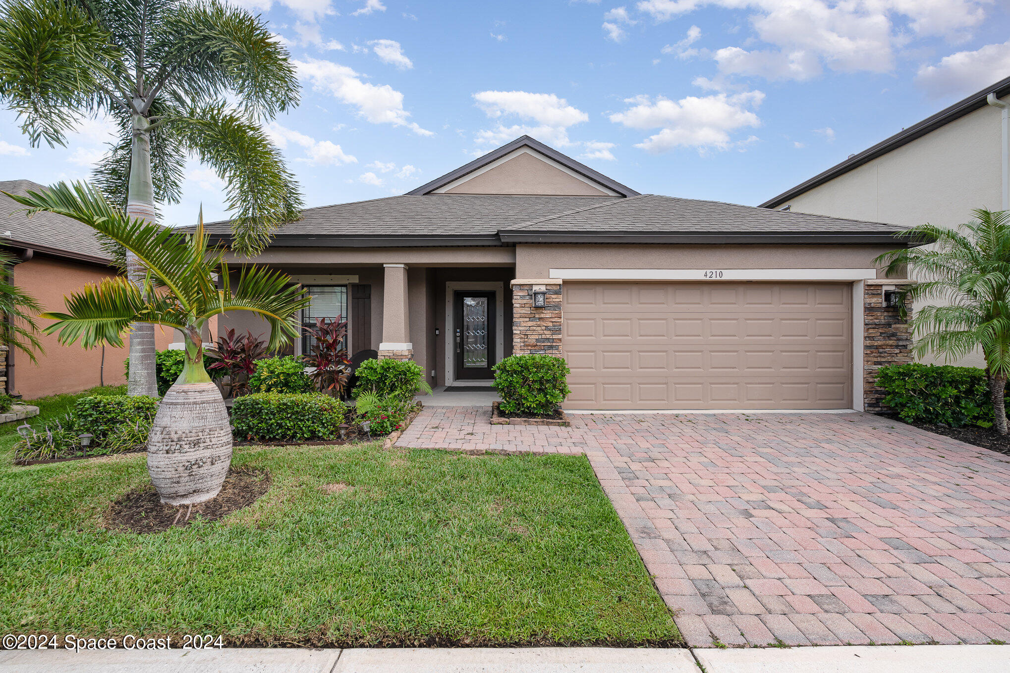 a front view of a house with a yard and palm tree