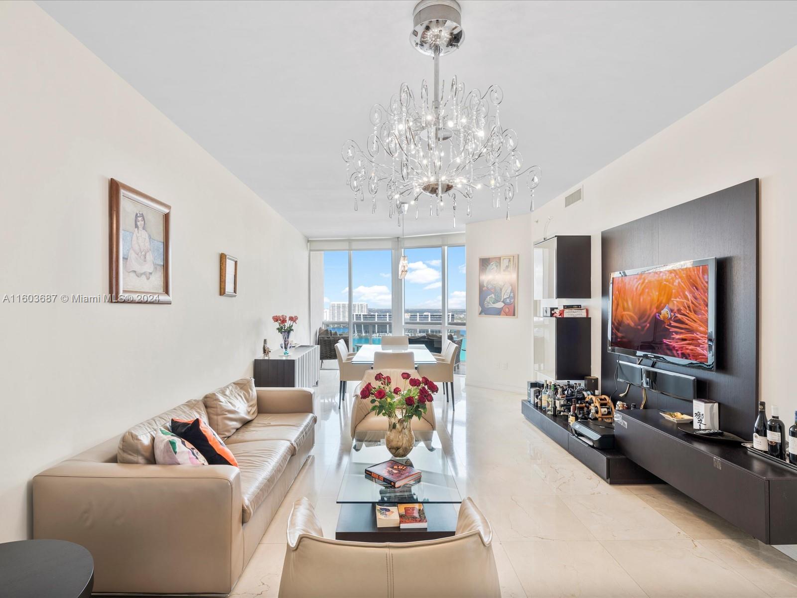 a living room with furniture a chandelier and a flat screen tv