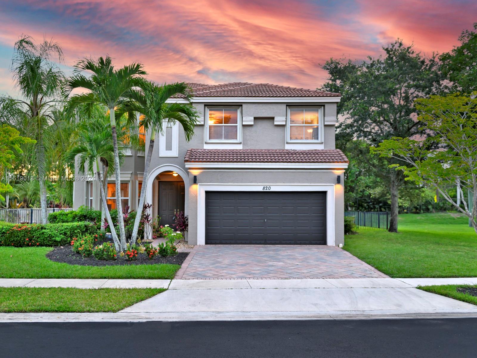 a front view of a house with a garden and trees