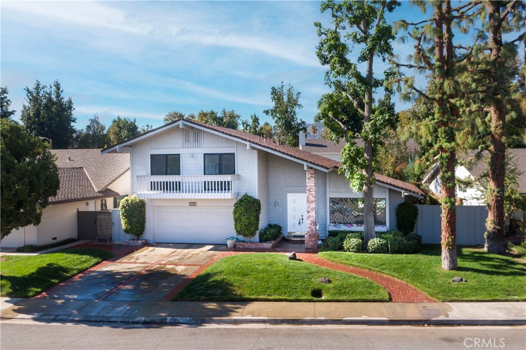 a view of a yard in front of a house with plants and large tree