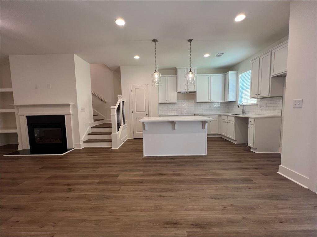 a room with stainless steel appliances wooden floor and a kitchen view