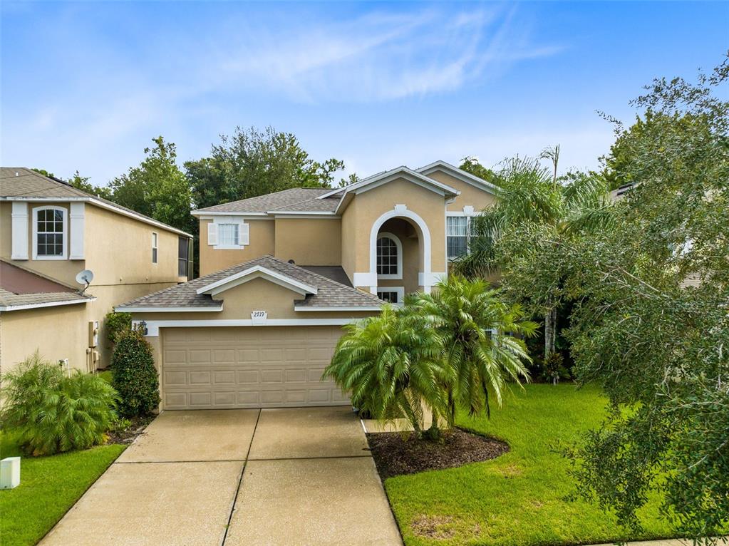 a front view of a house with a yard and trees