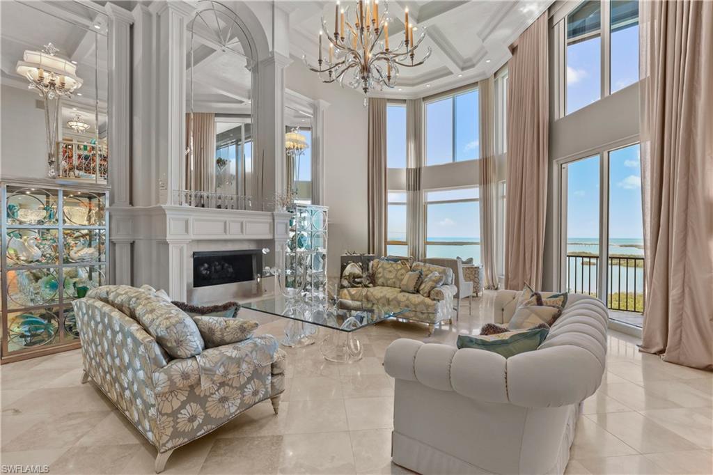 a living room with furniture large windows and fireplace