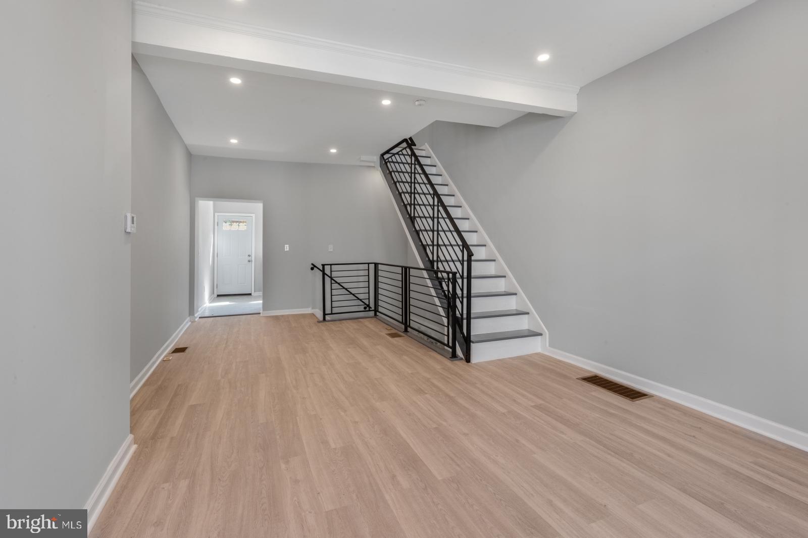 an empty room with wooden floor and staircase