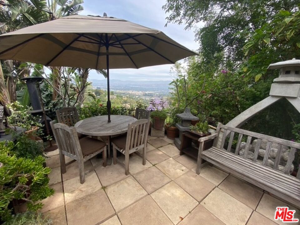 a backyard of a house with table and chairs under an umbrella