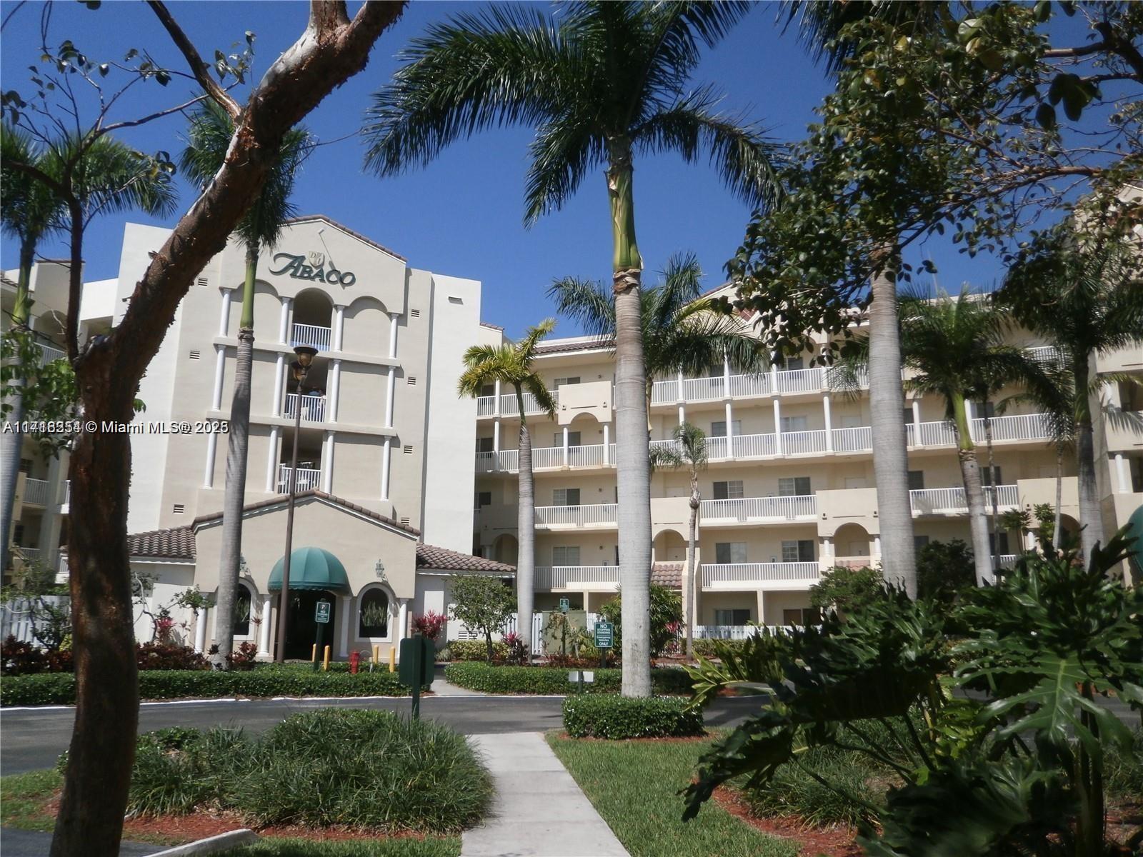 front view of a building with a yard and palm trees