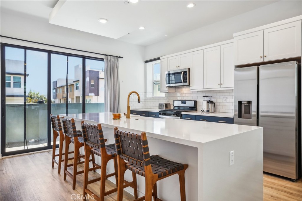 a large kitchen with kitchen island a large window and stainless steel appliances