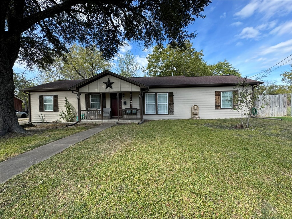 Ranch-style house with covered porch and a front y