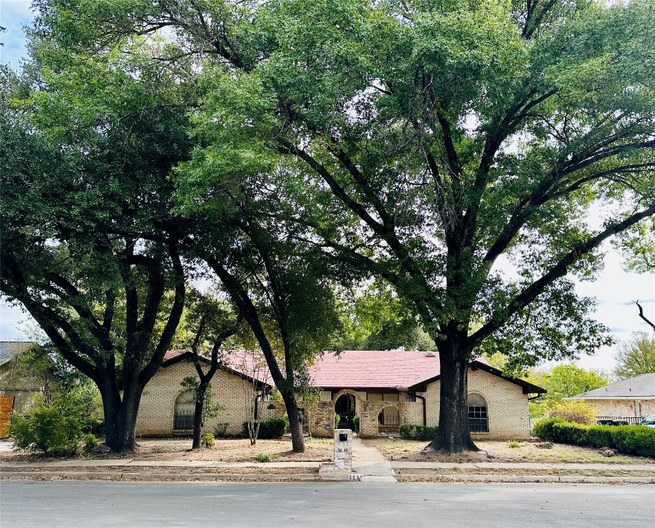 a front view of a house with a yard and large trees