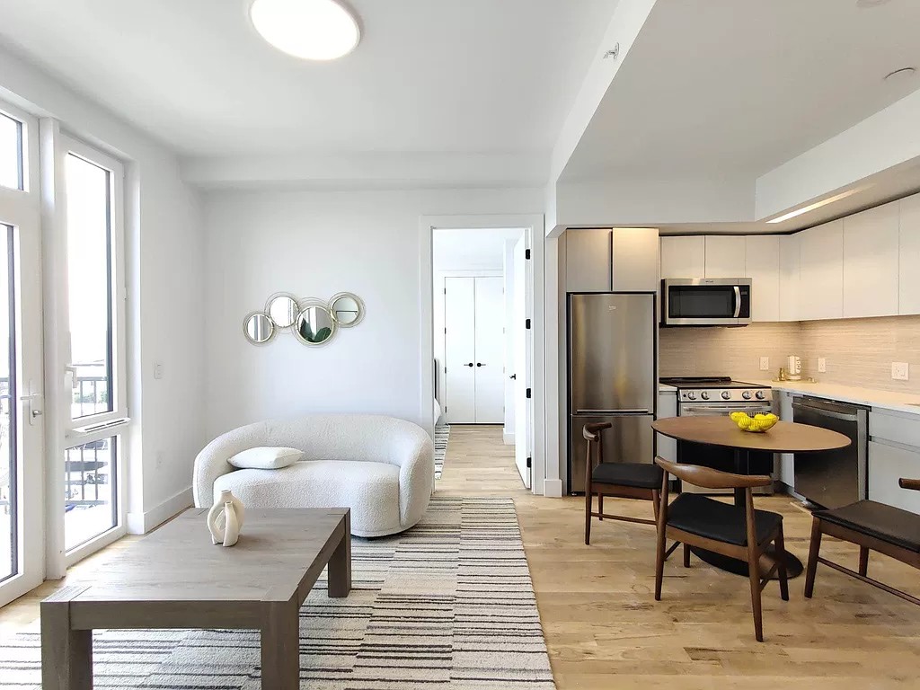 a living room with stainless steel appliances furniture a rug and a window