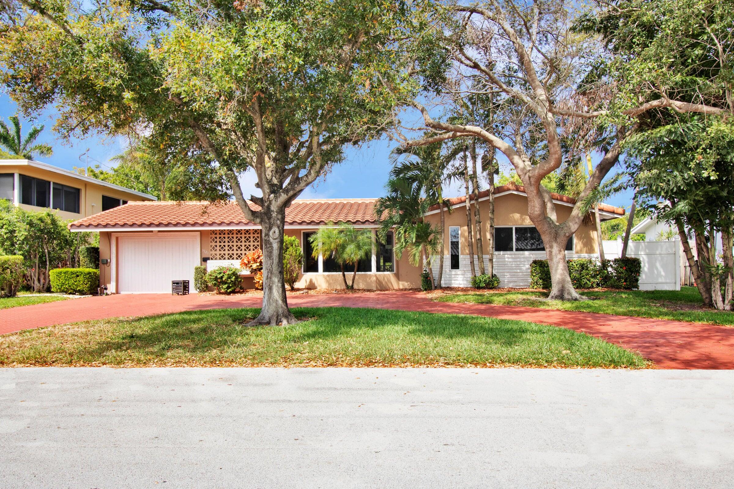 a view of a house with a yard and palm trees