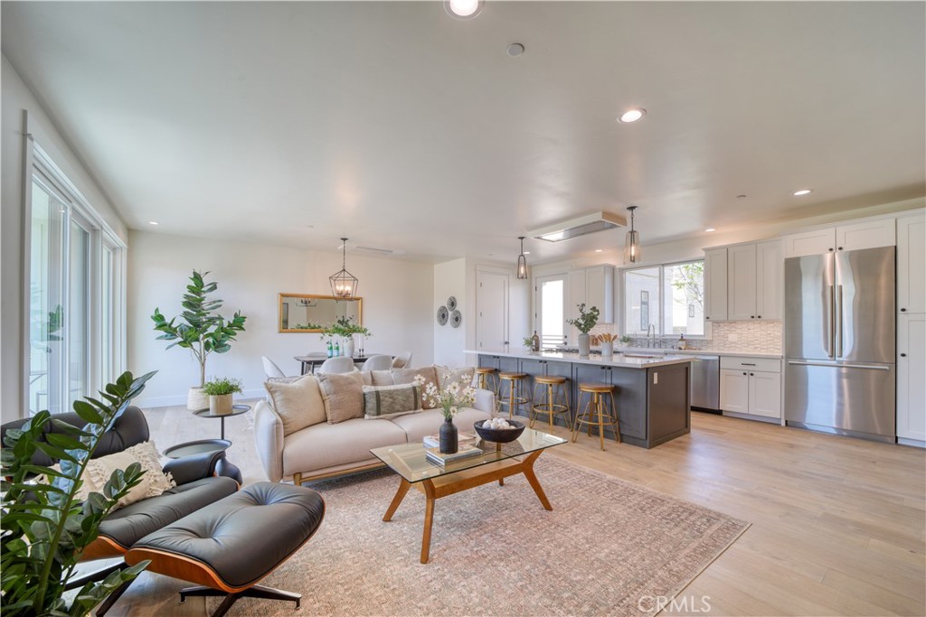 a living room with furniture a dining table wooden floor and kitchen view