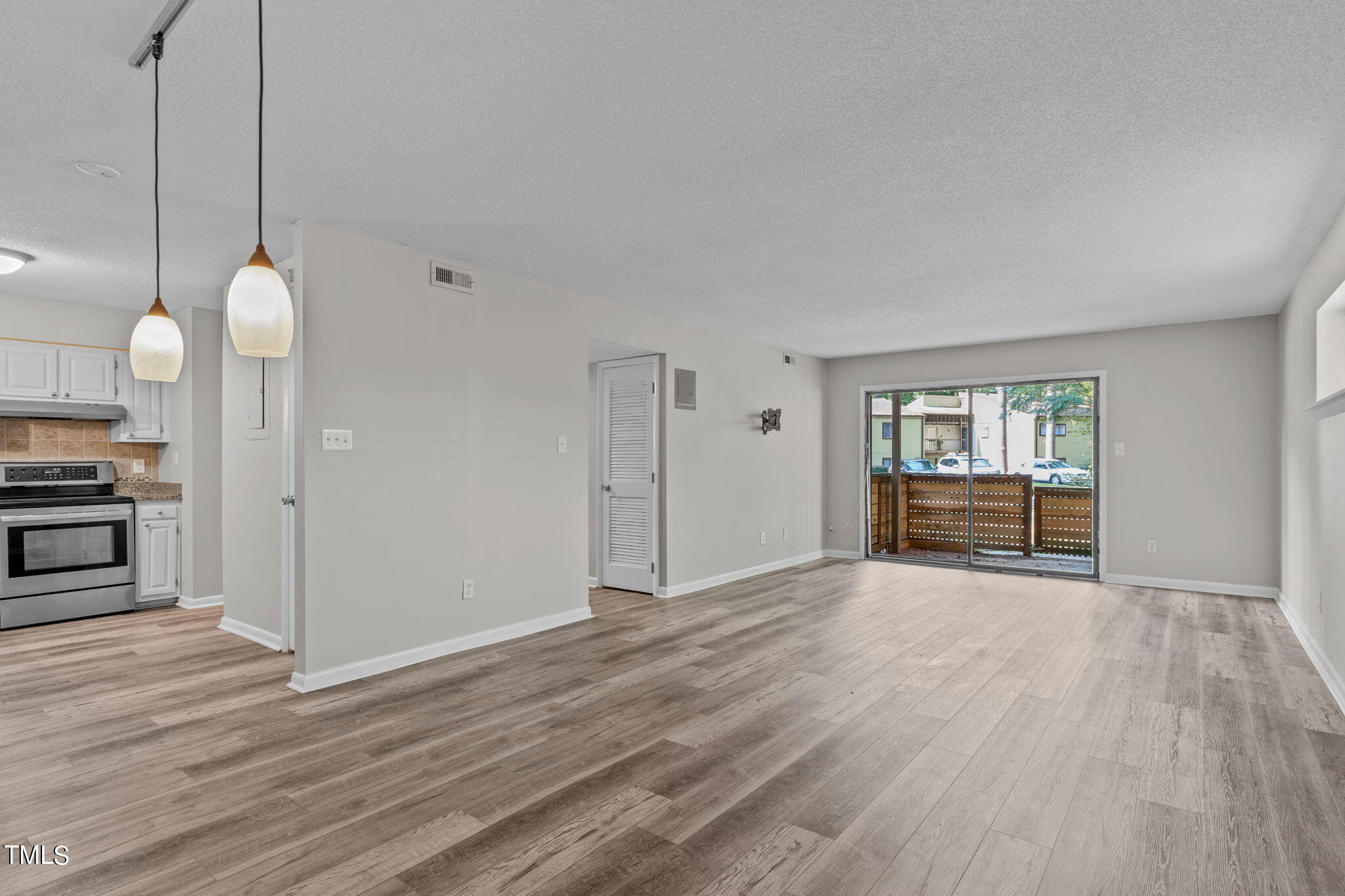 a view of an empty room with window and wooden floor