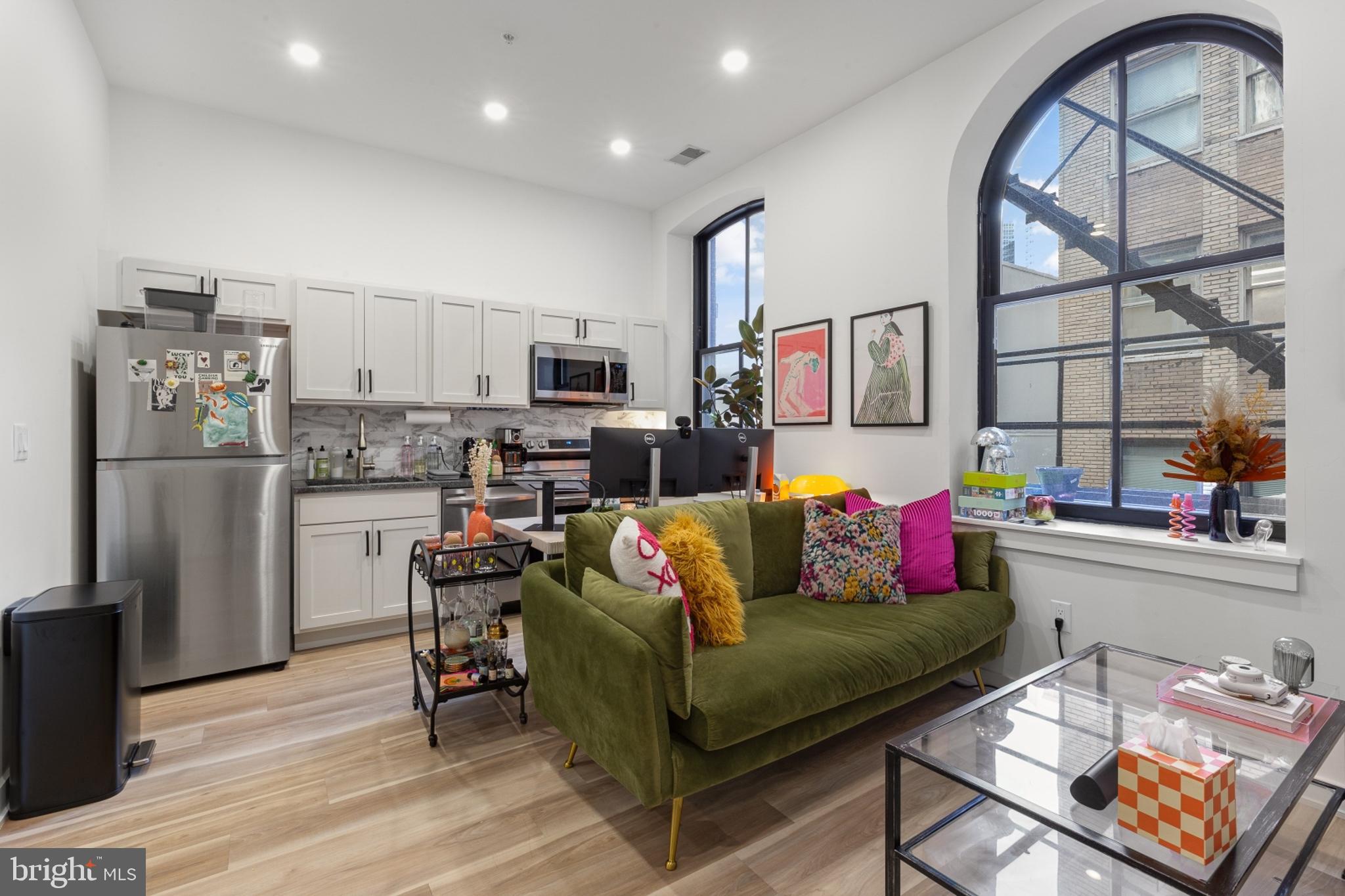 a living room with furniture a flat screen tv and a refrigerator