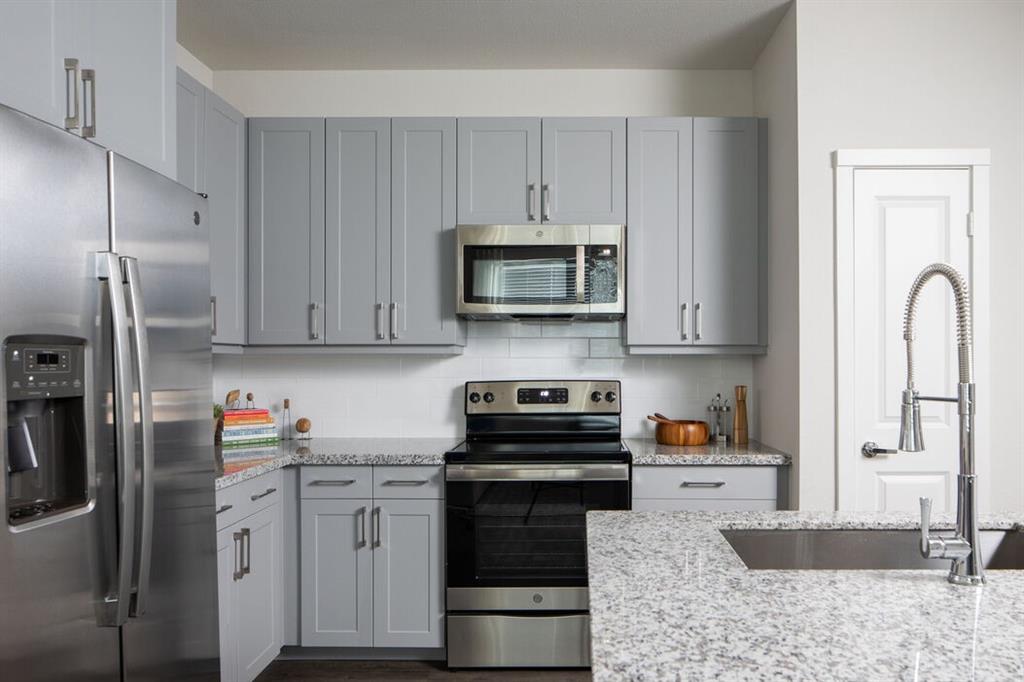 a kitchen with granite countertop a refrigerator stove and microwave