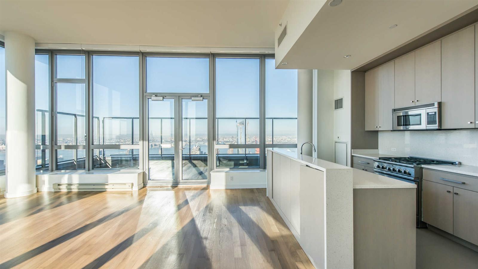 a kitchen with stainless steel appliances wooden floor and a large window