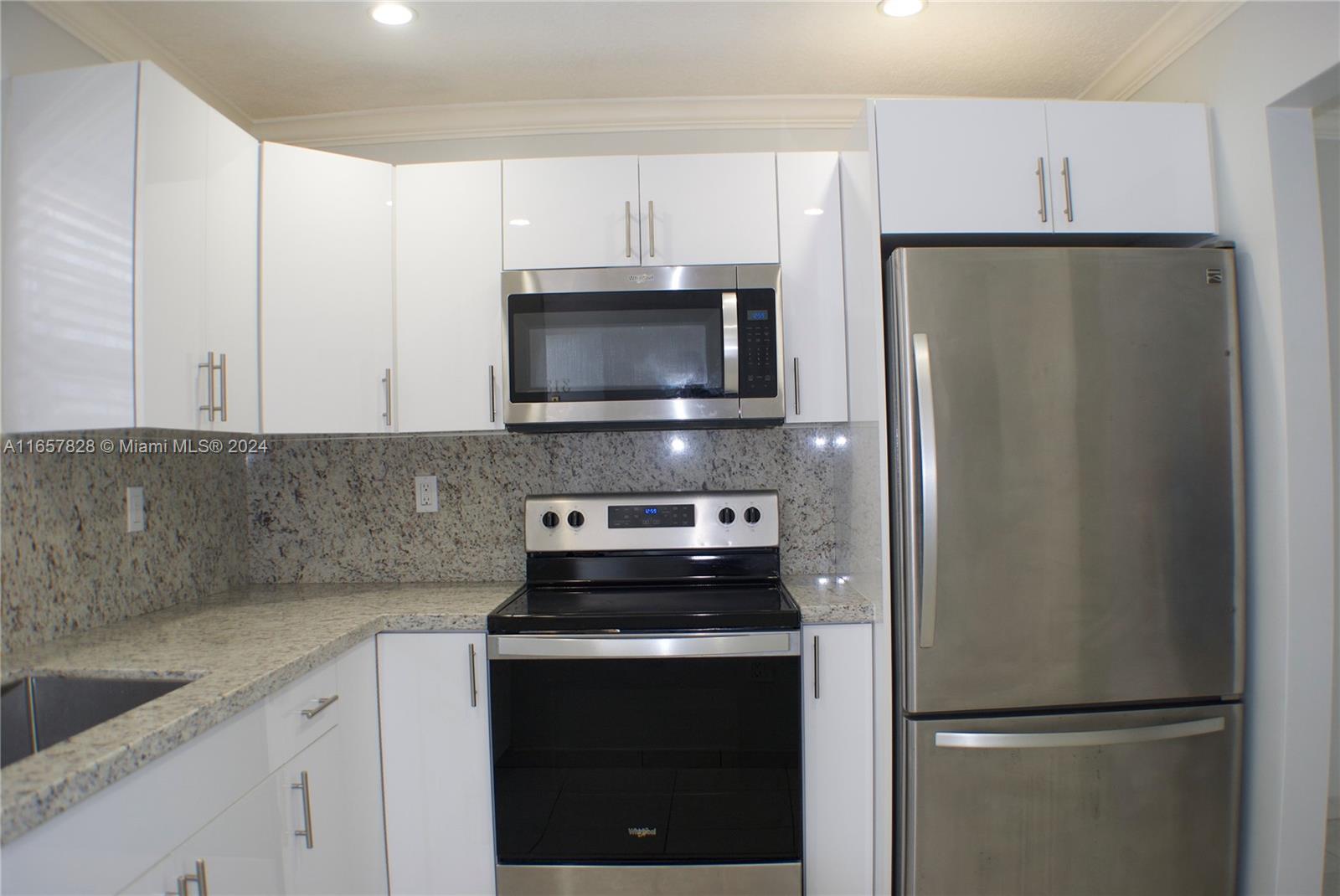 a kitchen with refrigerator a microwave and white cabinets