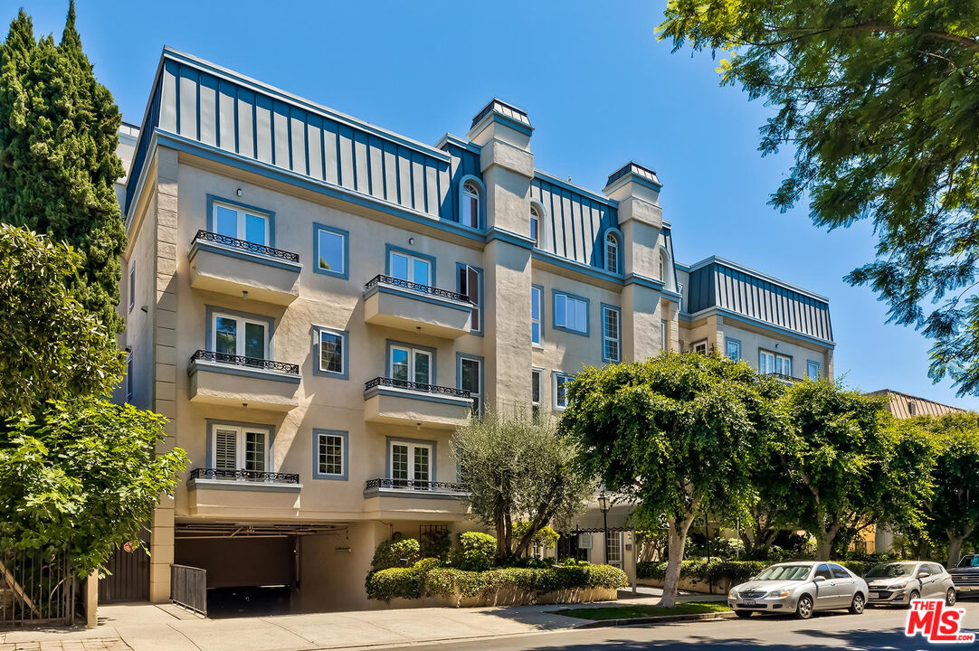 a front view of a building with lot of cars and trees