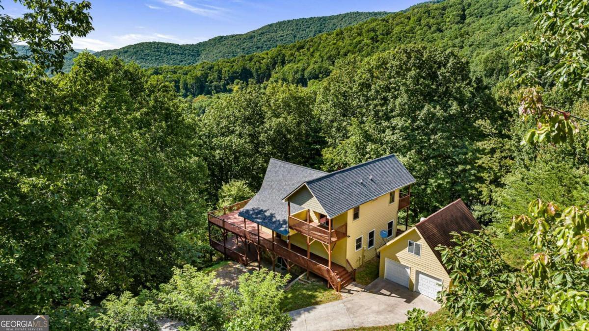 an aerial view of a house with a yard and mountain