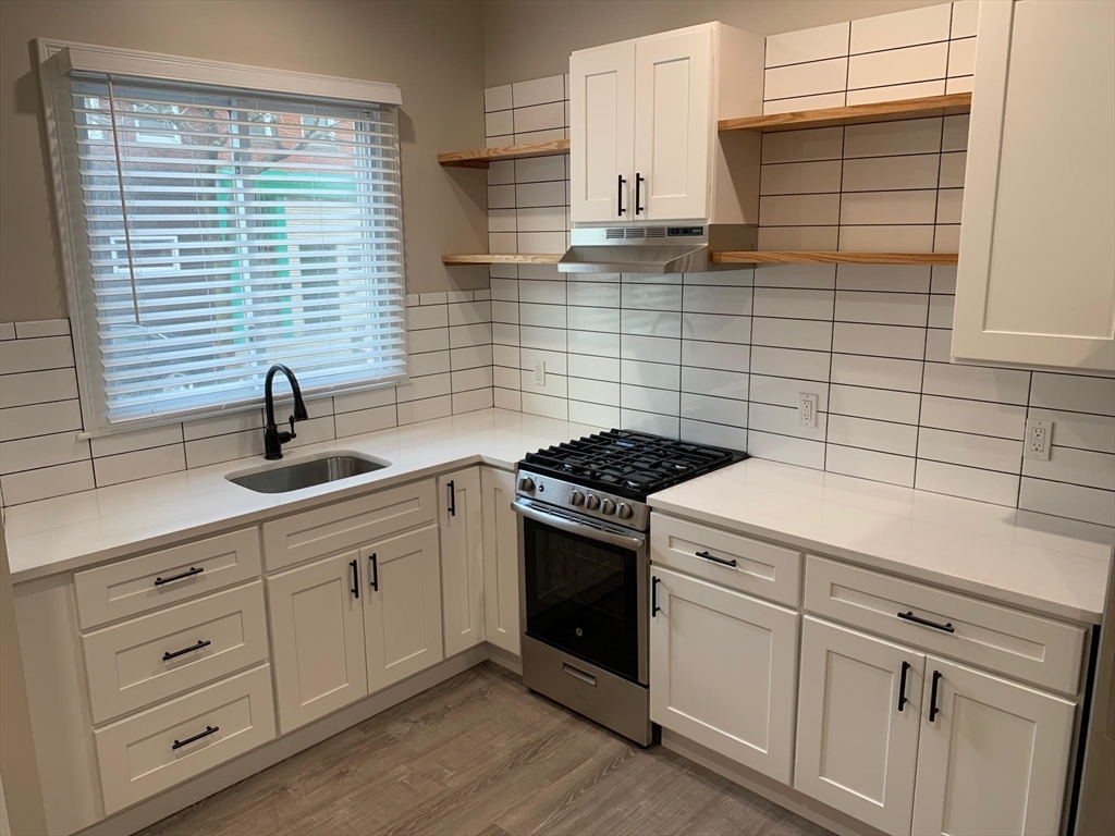 a kitchen with white cabinets and sink