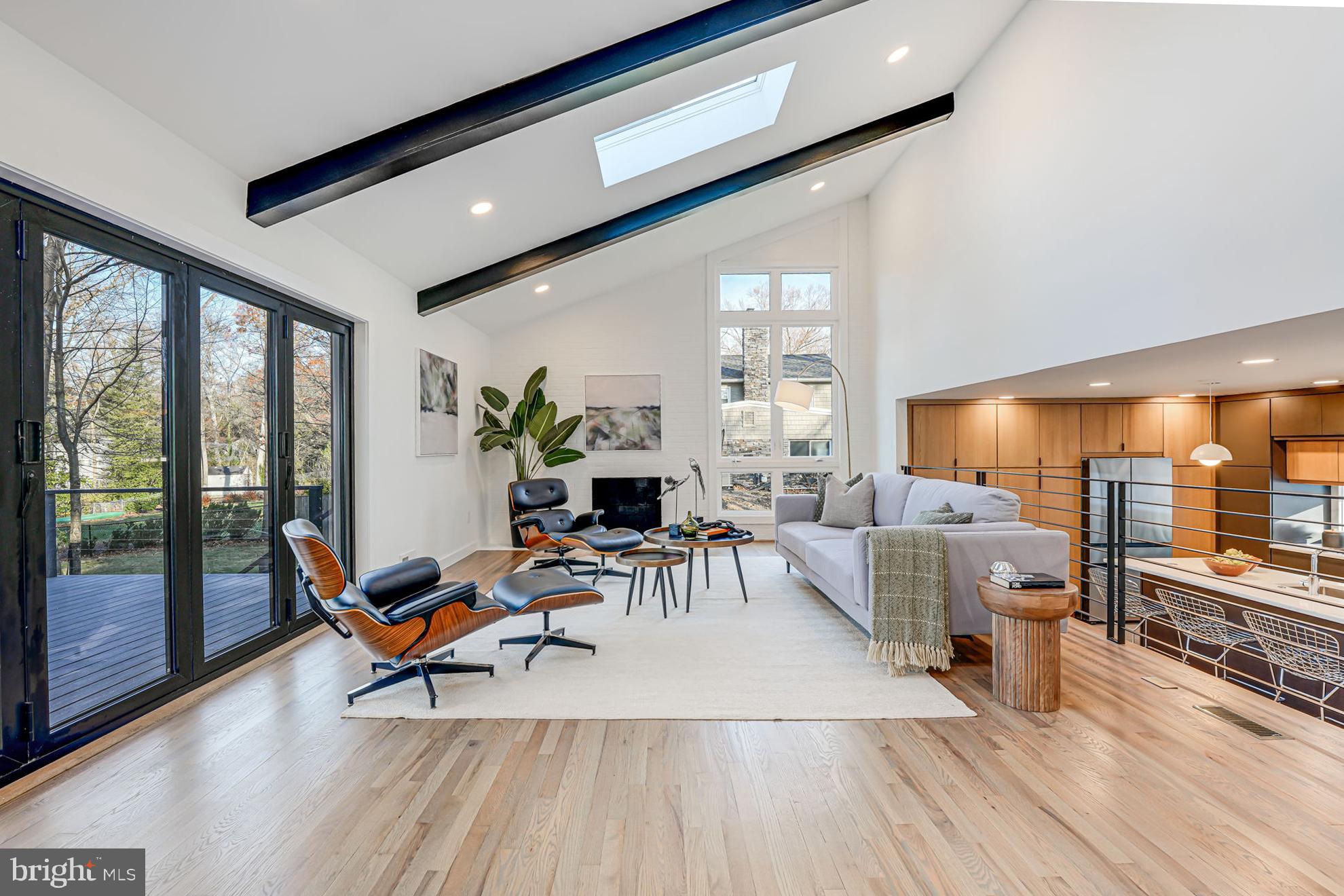 a living room with furniture a flat screen tv and floor to ceiling window