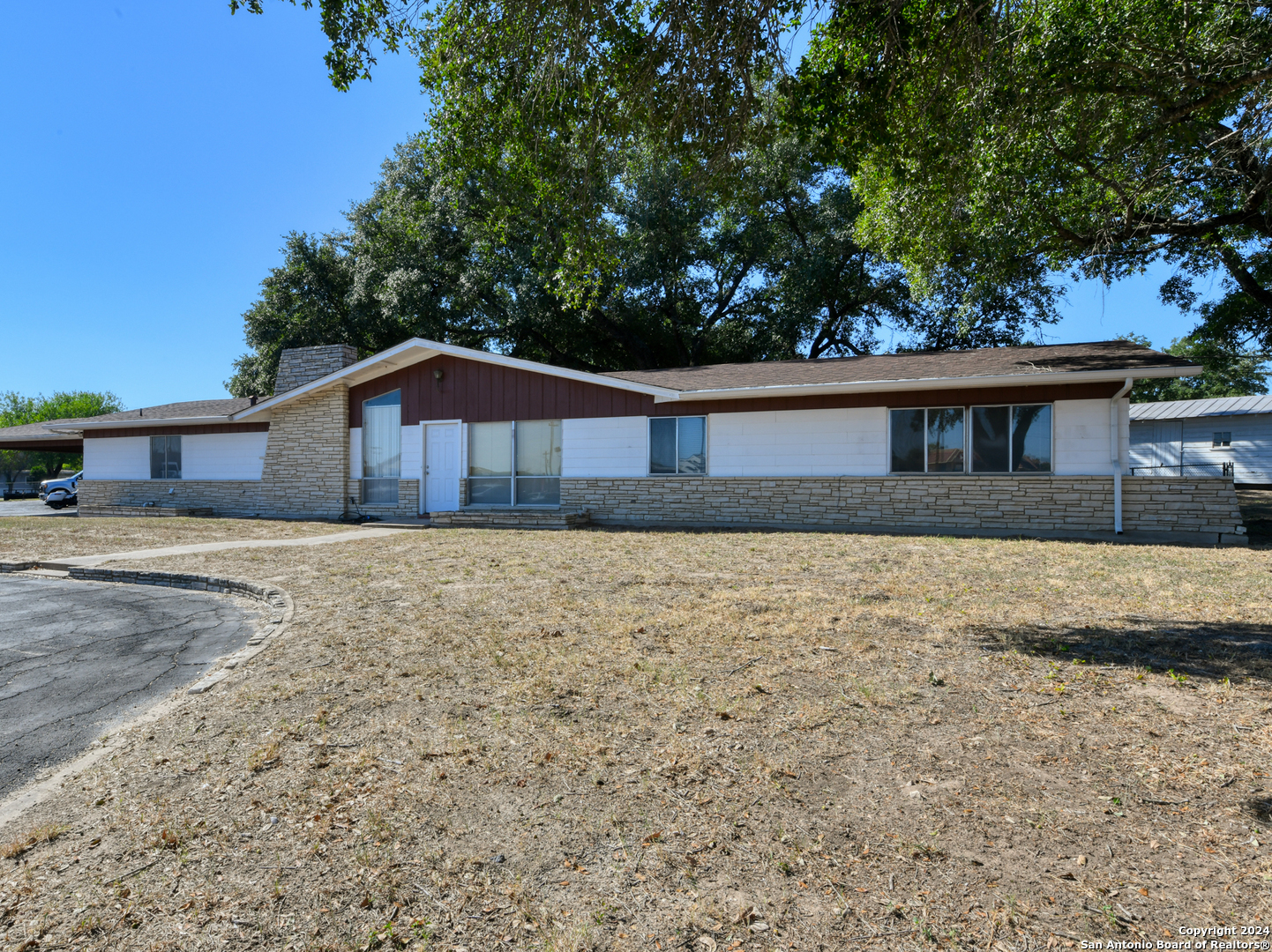 a front view of a house with large trees