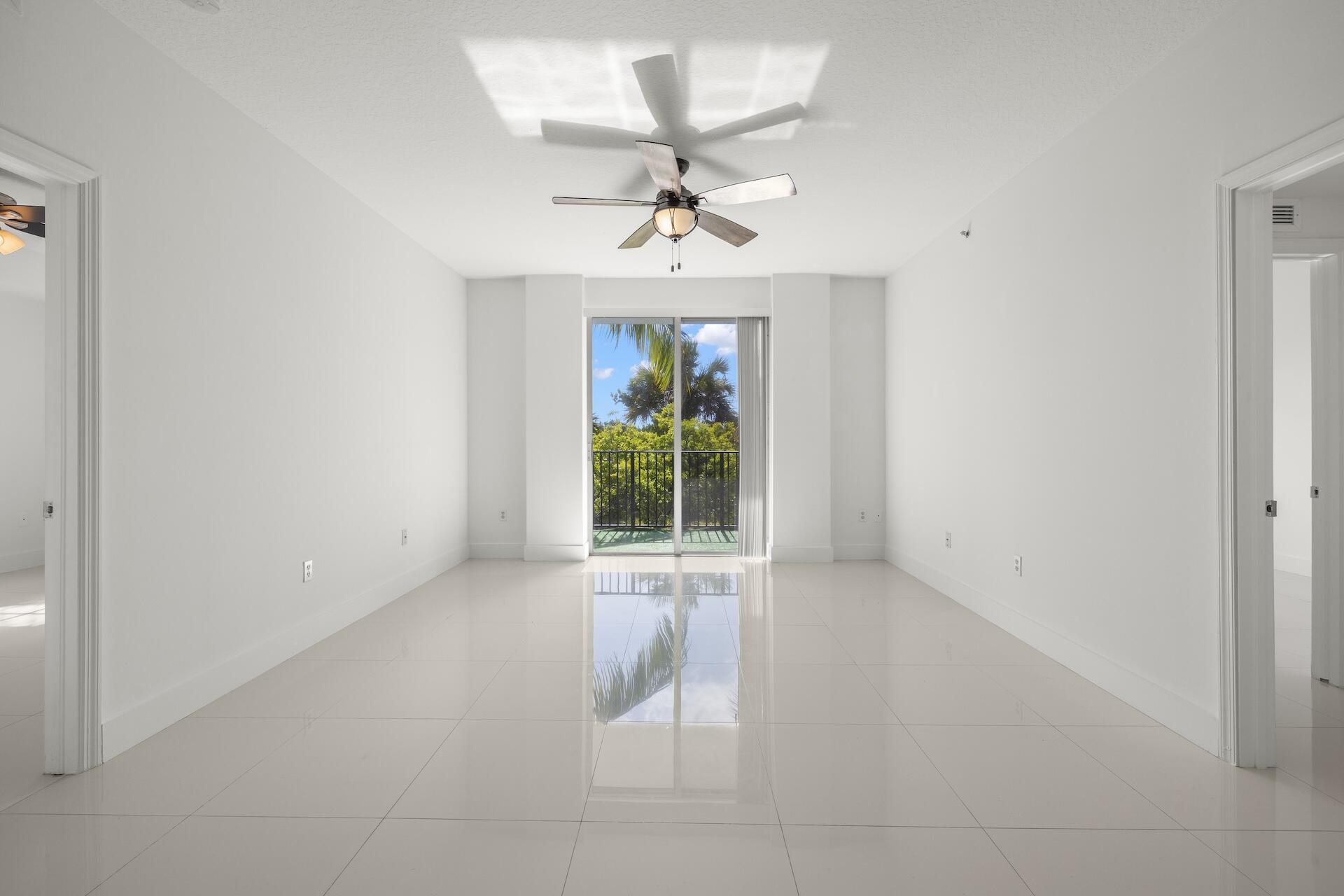 an empty room with windows and ceiling fan