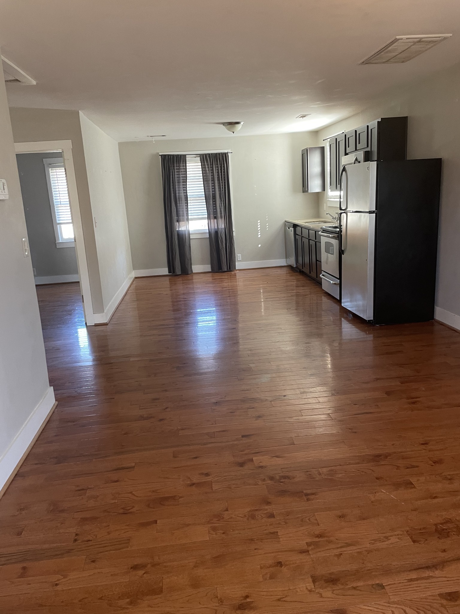 a view of a electric appliances in kitchen and empty room with wooden floor