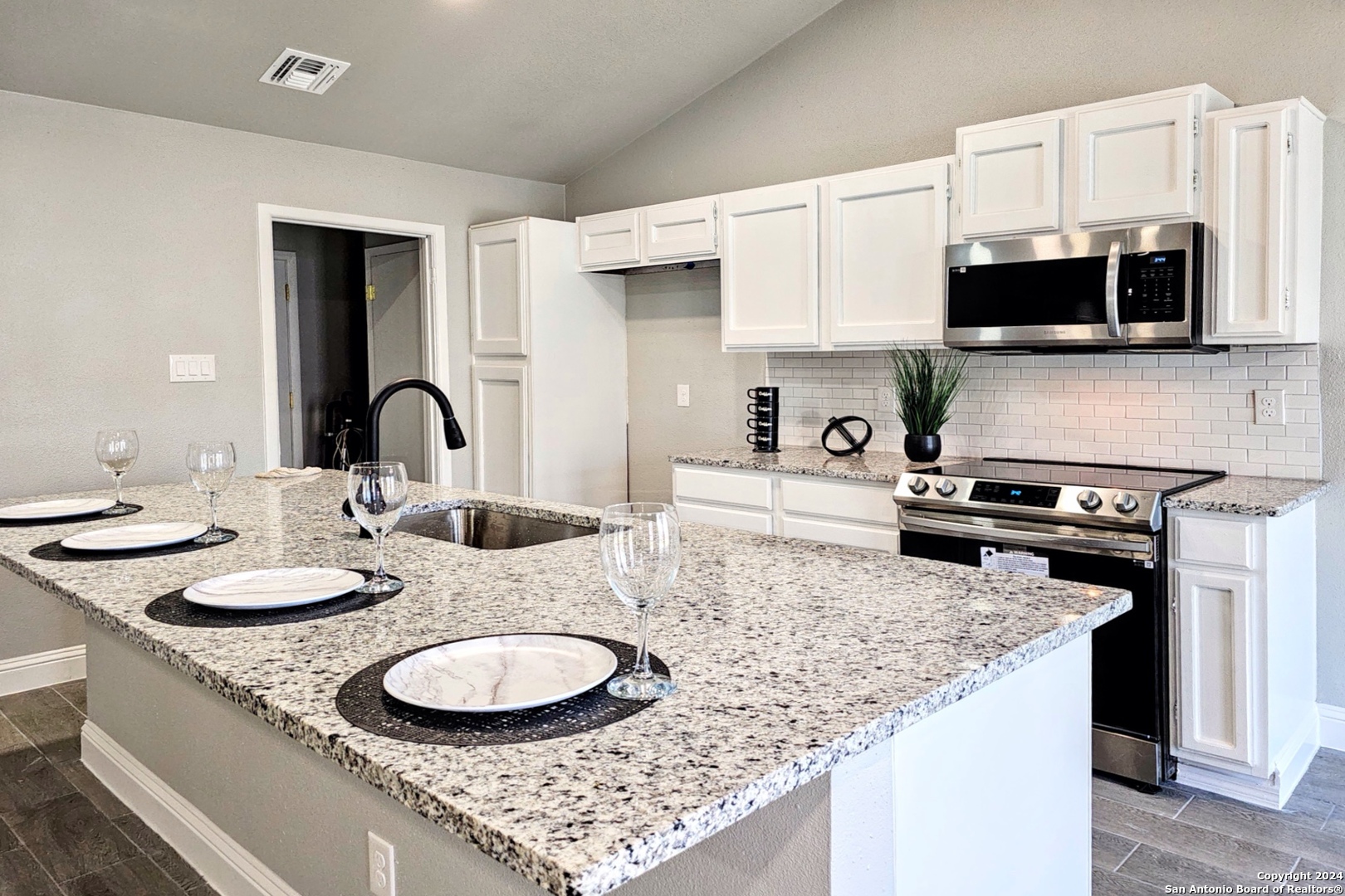 a kitchen with stainless steel appliances granite countertop a sink a stove a microwave and wooden cabinets