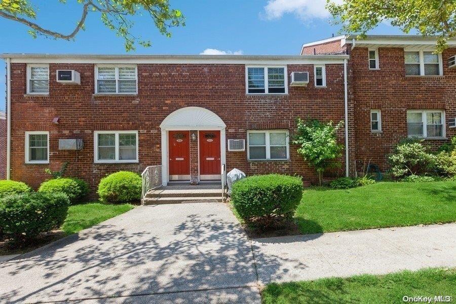 View of front of property featuring an AC wall unit and a front lawn