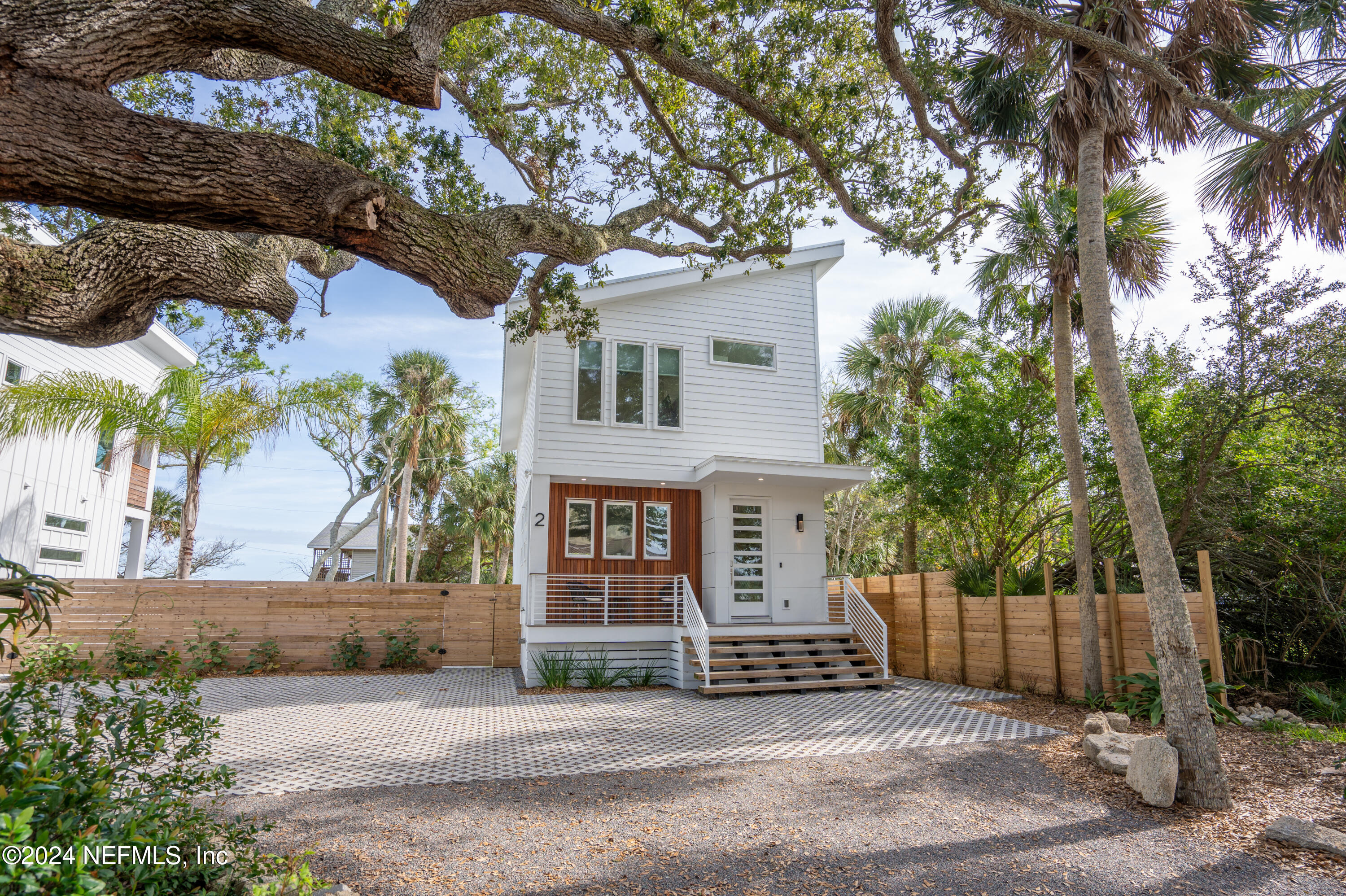 a view of a white house with a tree and wooden fence