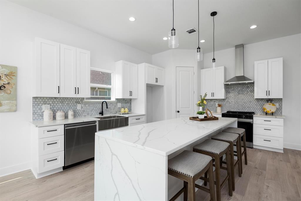 a kitchen with stainless steel appliances kitchen island a table chairs sink and cabinets